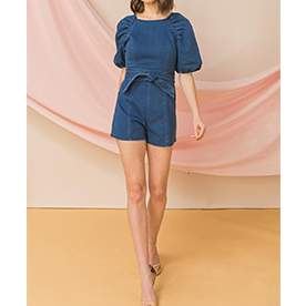 Denim romper featuring round neckline, ruched raglan sleeves, self sash tie and back zipper closure.